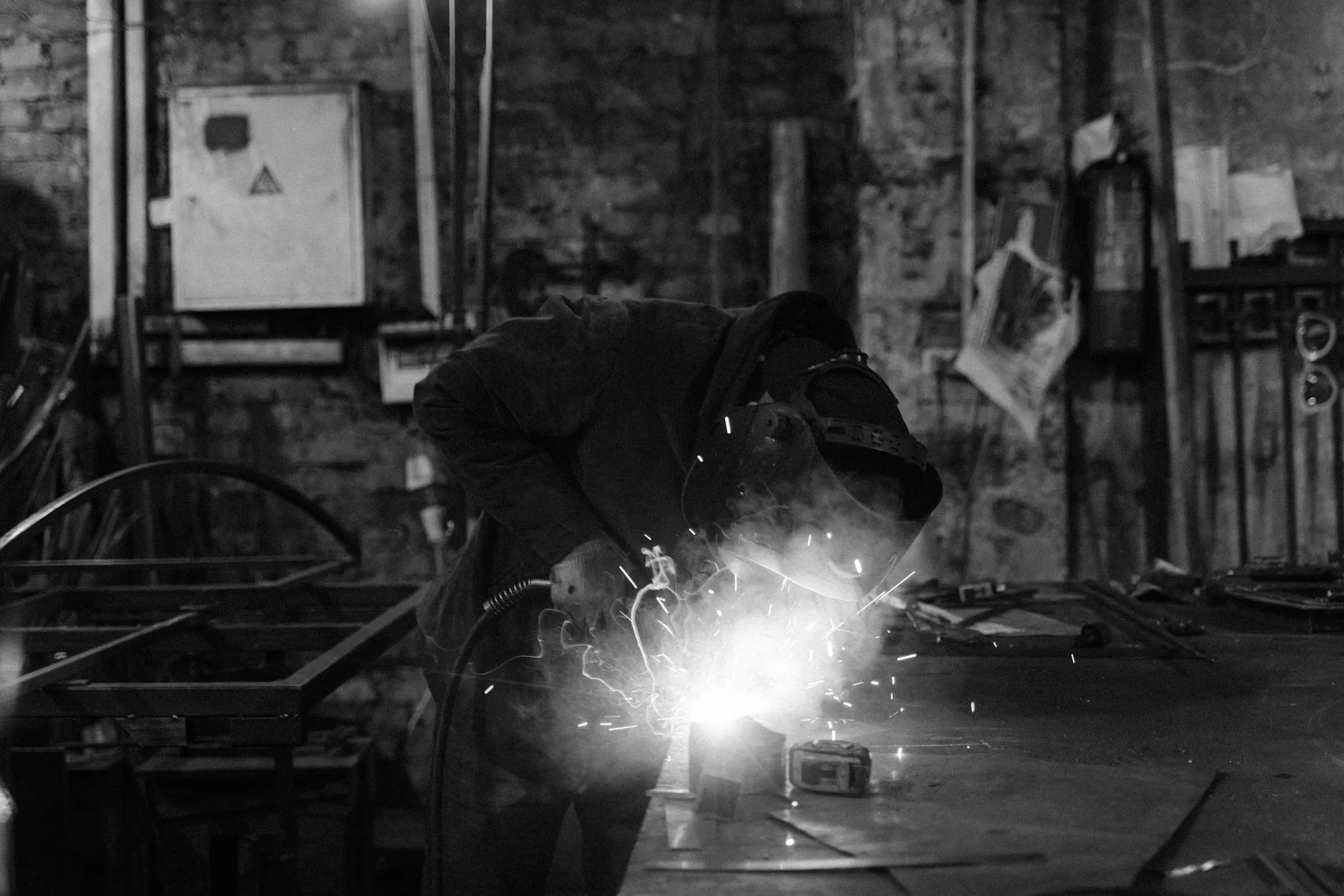 Welder producing sparks on a metal workpiece in a fabrication shop